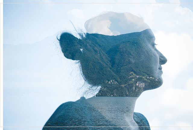 Image of a woman looking away in reflection overlaying a mountain and lake scene