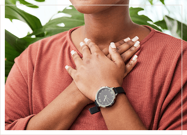 closeup of woman of african american descent with her hands held over her upper chest and heart area